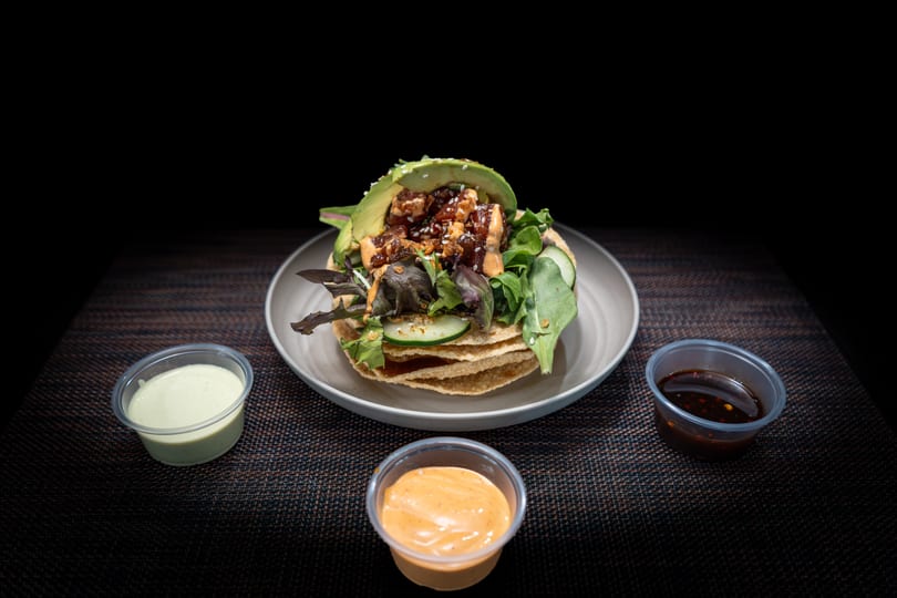 Tuna poke tostada with avocado, greens, and cucumber, served with three dipping sauces.
