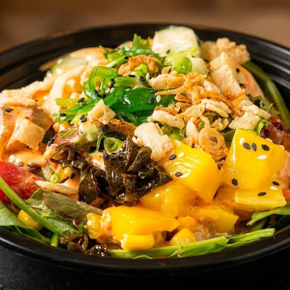 A colorful poke bowl with tuna, mango, seaweed, crispy onions, and a creamy sauce.