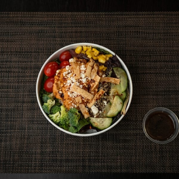 Overhead view of a colorful salad bowl with hummus, tortilla strips, and vegetables.
